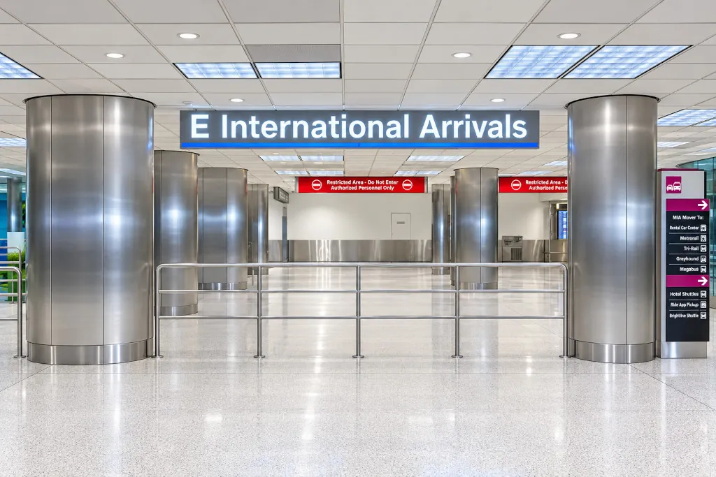 E International Arrivals exit in the Central Terminal at Miami International Airport, with signs to the MIA Mover, Rental Car Center and ride app pickup